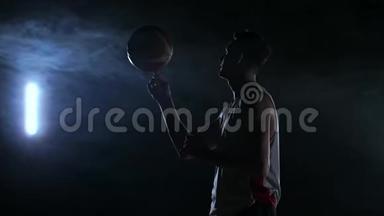 近镜头篮球运动员旋转球在他的手指，黑暗的雾室与泛光灯